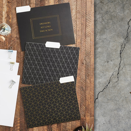 Three black folders with geometric patterns on a wooden surface.