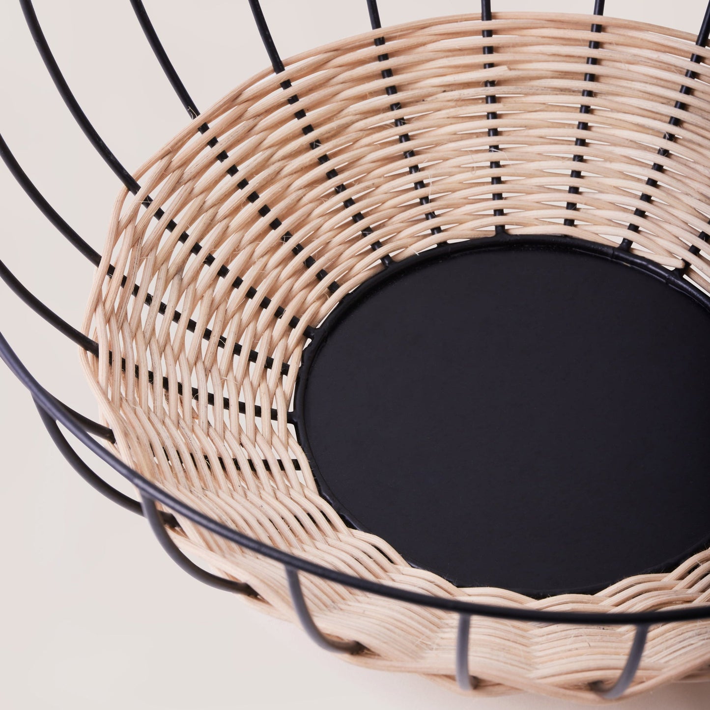 Close-up of a wicker chair with a black cushion on a light background