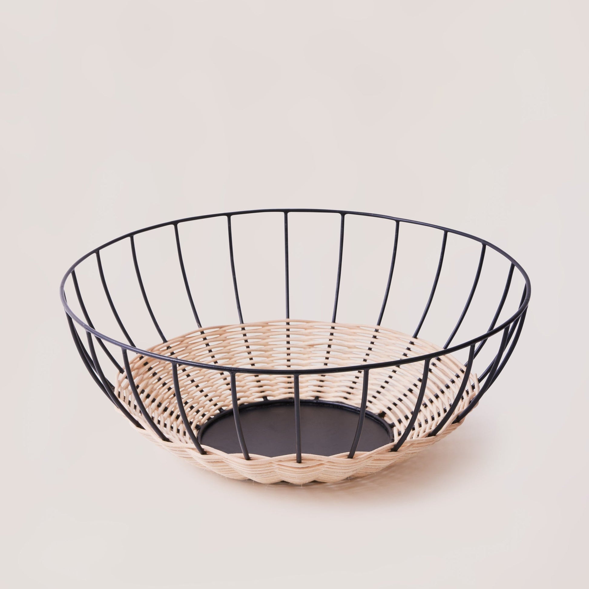 Wire fruit basket with woven base on a light background