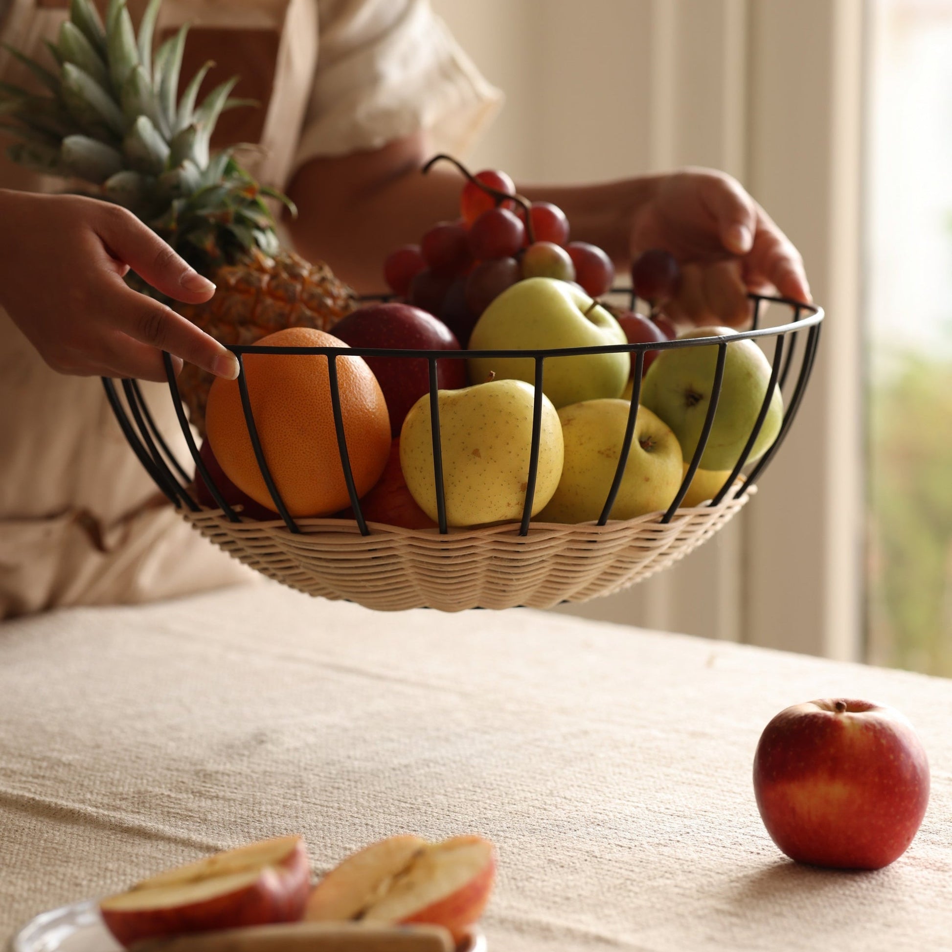 Fruit basket with apples, oranges, and grapes on a table.