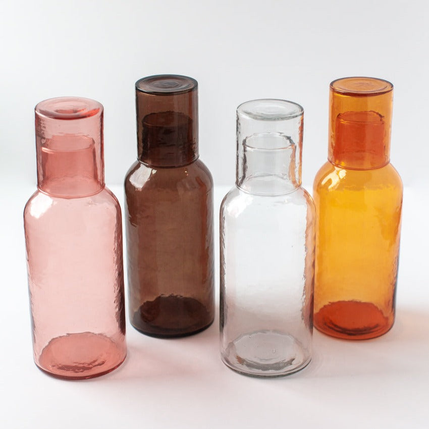 Five glass bottles of different colors on a white background