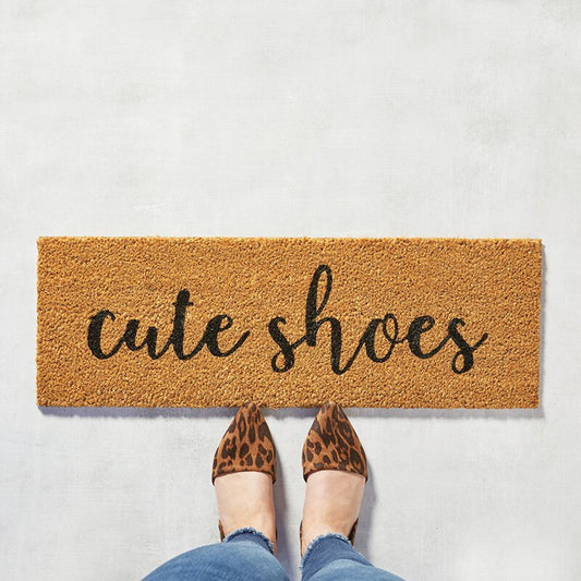 Doormat with 'cute shoes' text on a light gray background