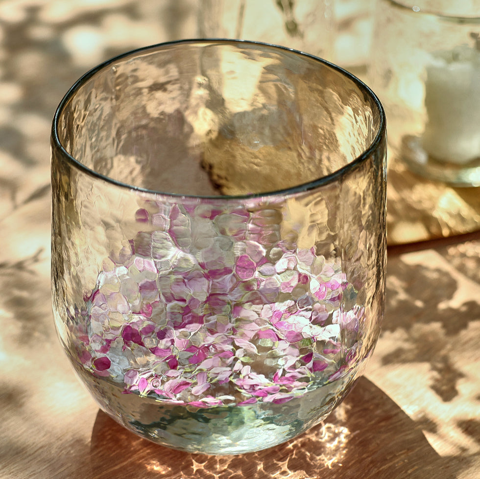 Clear glass filled with pink and white confetti on a wooden surface