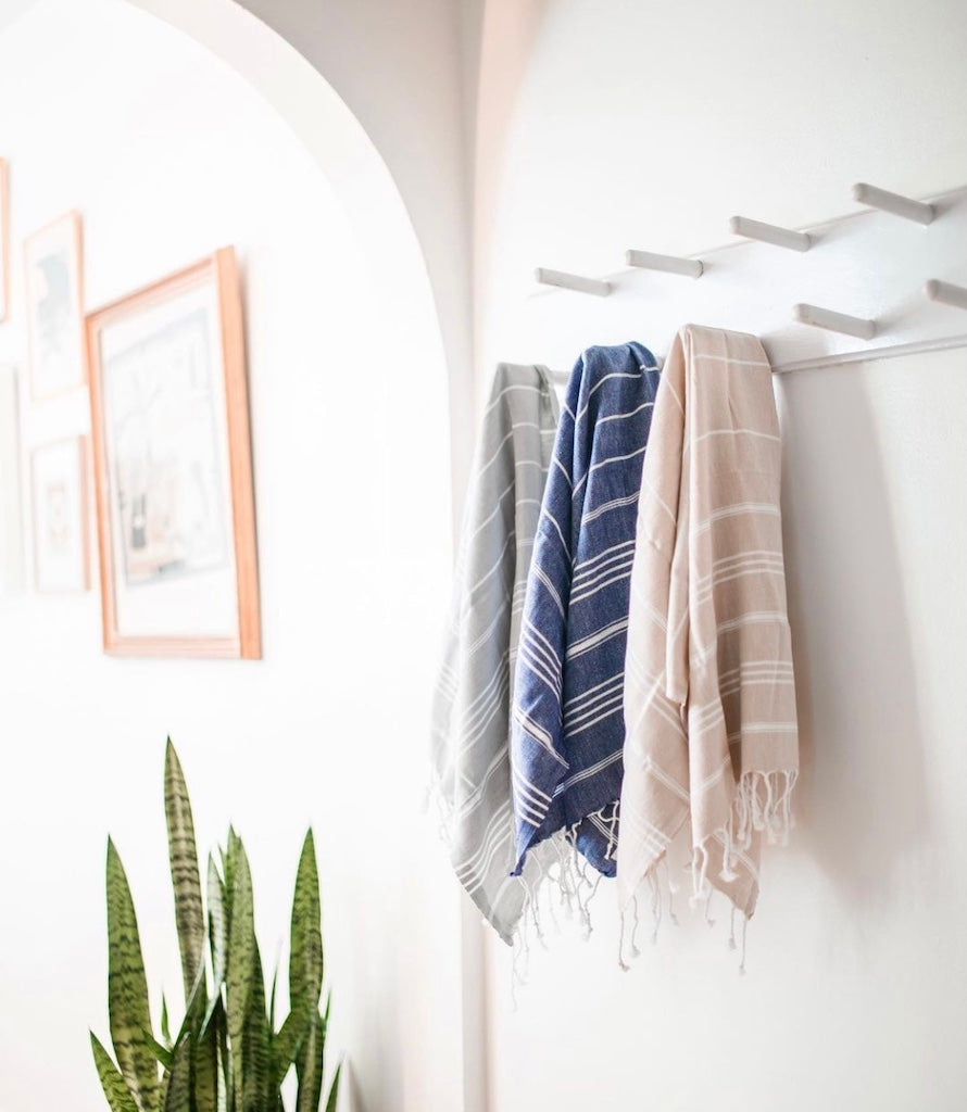 Towels hanging on a rack with a plant in the foreground