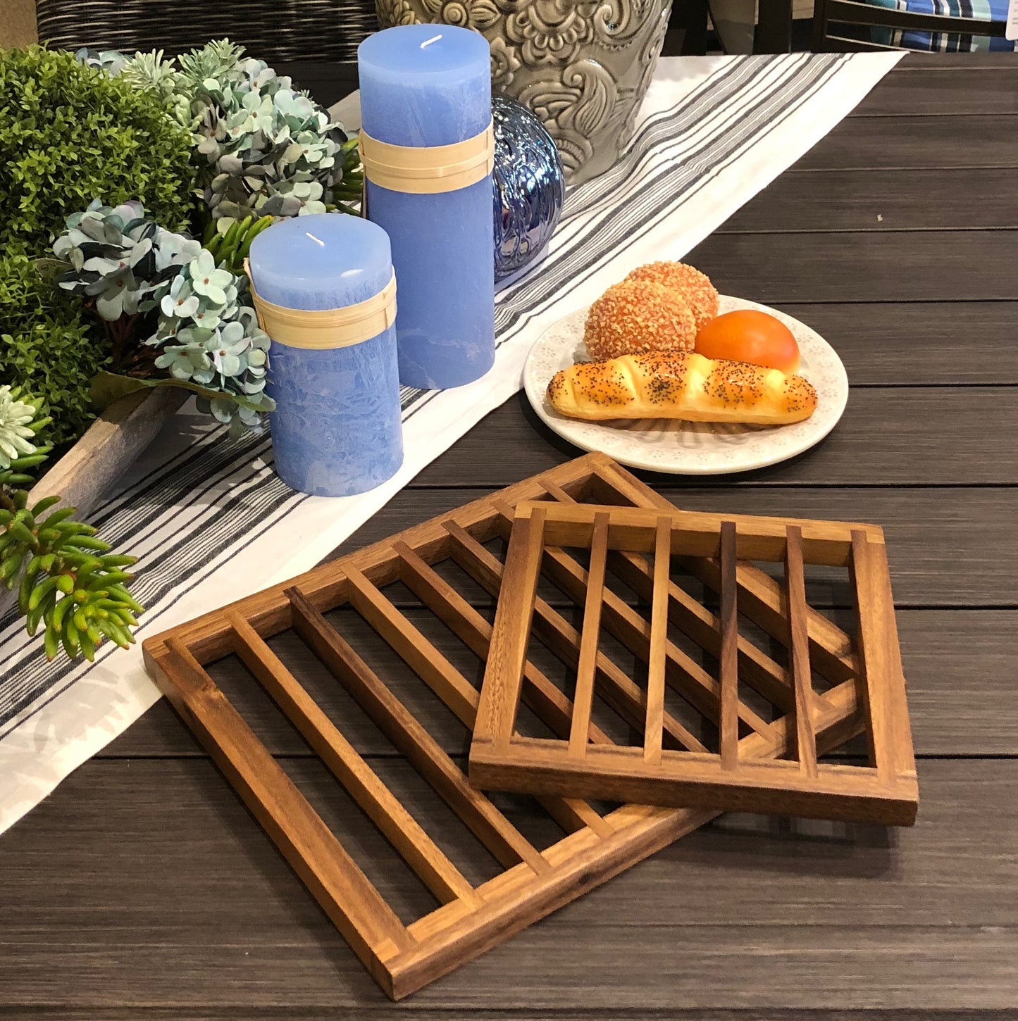 Wooden trivet with blue candles and food on a wooden surface