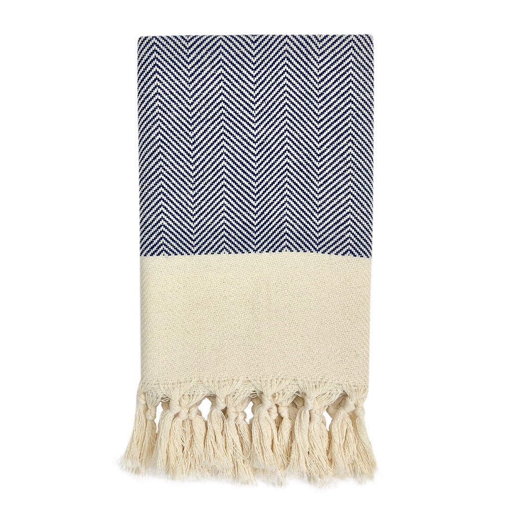Towel with blue and white chevron pattern and beige tassels on a white background