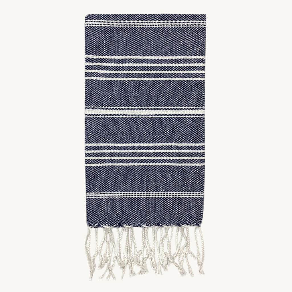 Navy blue towel with white stripes and fringes on a white background