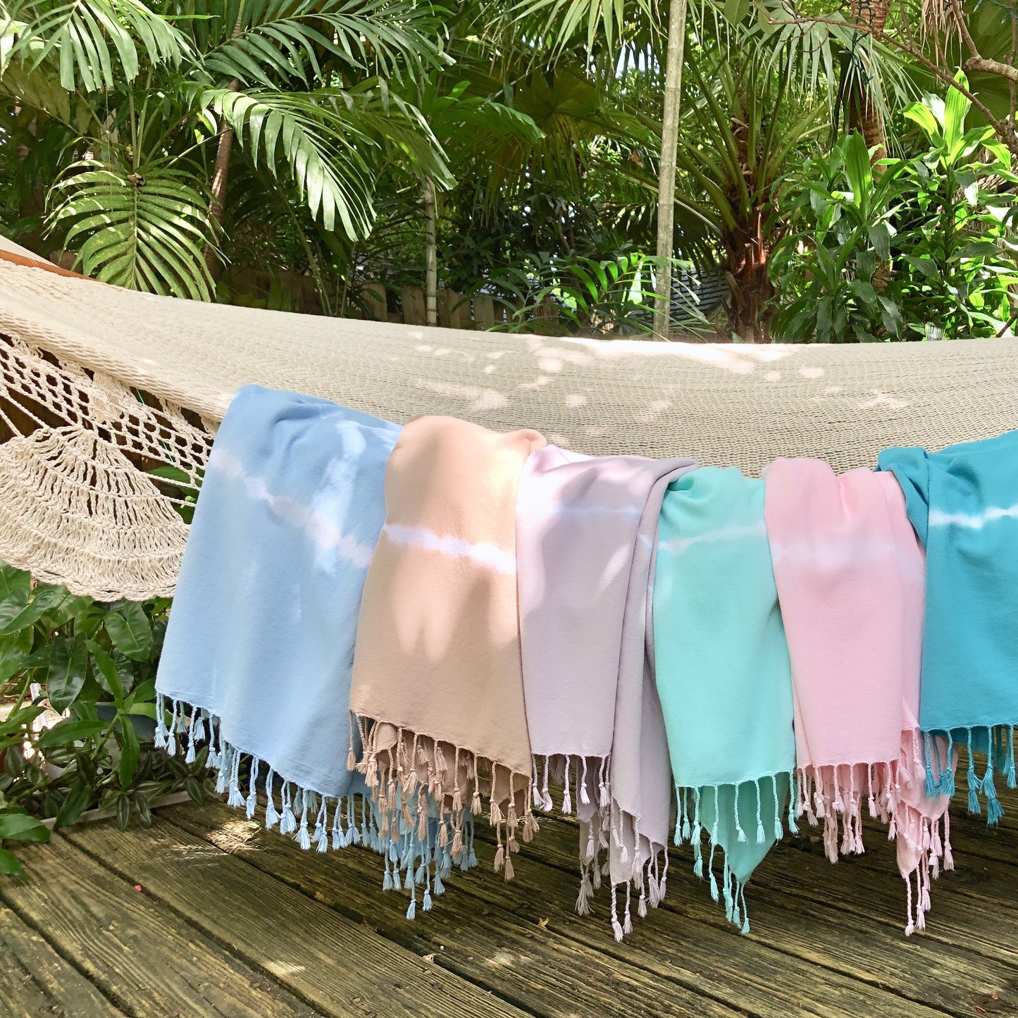 Colorful towels draped over a hammock with a tropical background