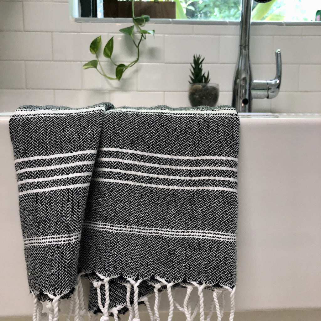 Black and white striped towel draped over a bathtub in a bathroom setting.